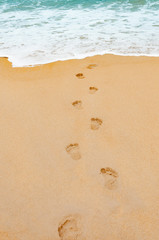 Footprints in the sea sandy beach , wave foam  on a vacation tim
