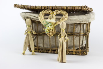 Two straw figurines in front of a vintage box