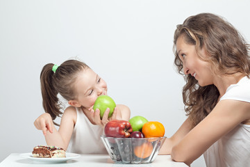 mother giving apple to convince her little daughter