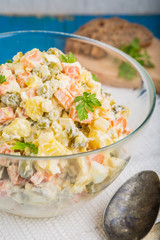 Salad olivier in bowl on blue table. Russian traditional salad.