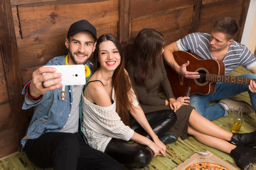 Happy friends making selfies and playing the guitar