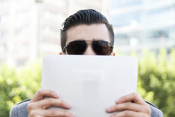 young hipster businessman holding the laptop in front of face