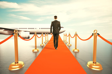 Businessman walking on red carpet to the first class of plane