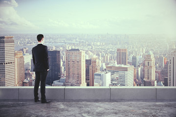 Businessman on the roof and looking at the city with skyscrapers