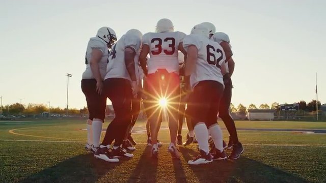 A football team in a huddle getting hyped in slow motion
