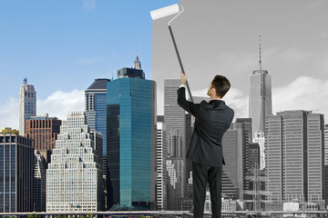 Fototapeta premium Businessman paints black and white city into colorful city, chan