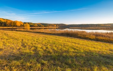 Obraz premium Beautiful autumnal landscape with grassland and lake