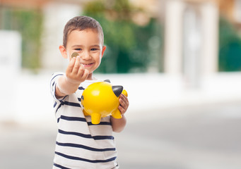 portrait of a little boy putting money on a moneybox