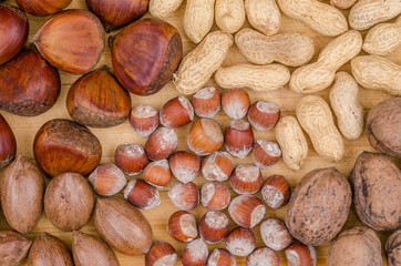 Raw hazelnuts, pecan nuts and chestnuts. Wooden background. Oleaginous