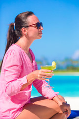 Young woman with tasty cocktail on white tropical beach