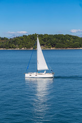 Sailing boat on blue sea waters with clear blue sky