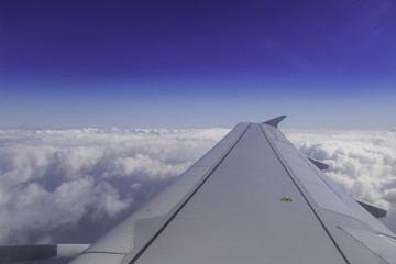 Fototapeta na wymiar Wing of airplane above the clouds in the sky, view from window.