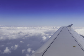 Fototapeta na wymiar Wing of airplane above the clouds in the sky, view from window.