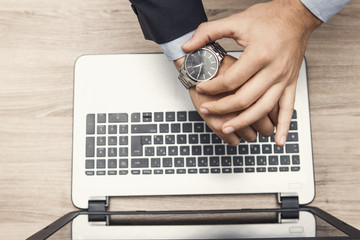 mano di uomo in ufficio con orologio al poloso e tastiera di notebook