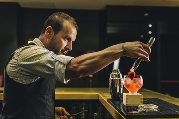 Barman is making cocktail at night club