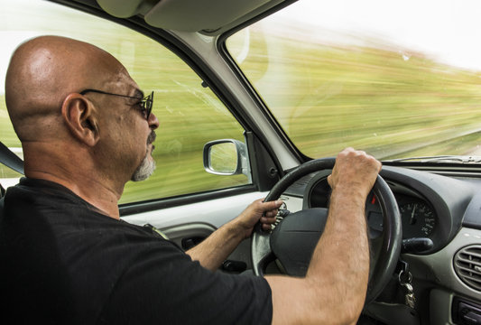 Hombre calvo viaja en su furgoneta a gran velocidad.
