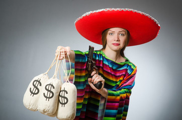 Girl in mexican poncho holding handgun and money sacks against g