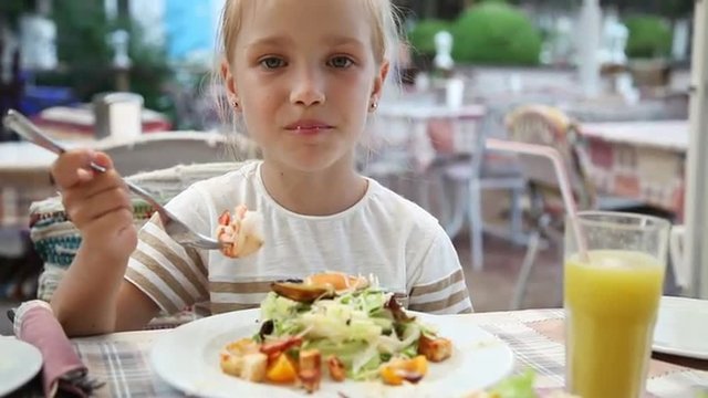 Girl eating big shrimp in a restaurant. She loves fish restaurant