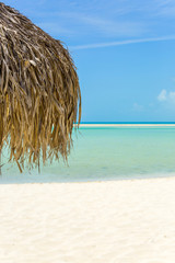 Fototapeta na wymiar Beach Umbrella made of palm leafs on exotic beach