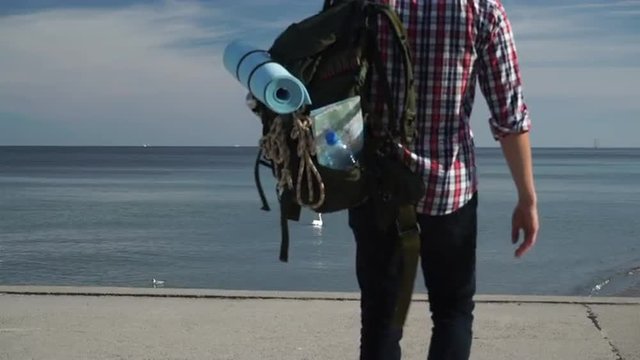 Man hiker with backpack tramping by seaside 4K