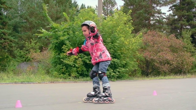 Little girl roller skating between cones in slow motion 