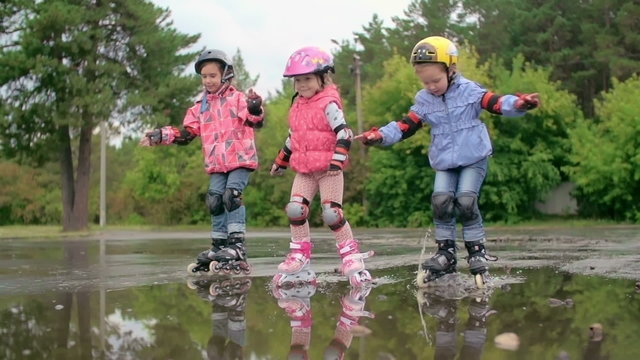 Group of kids roller skating through puddles in slow motion 