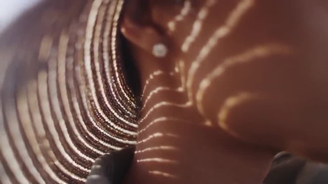 Extreme close up of Black woman with sunhat and diamond earing