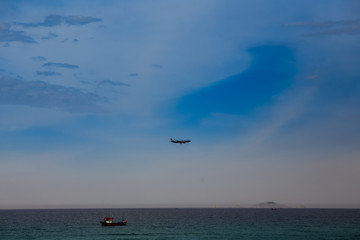 plane in sky above sea fishing boat green banner on foreground