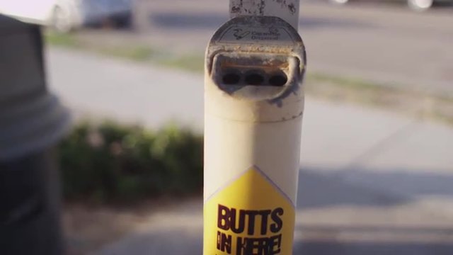 Cigarette butt disposal container with Butts In Here text sign