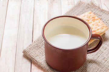 Milk with crackers on wooden table.