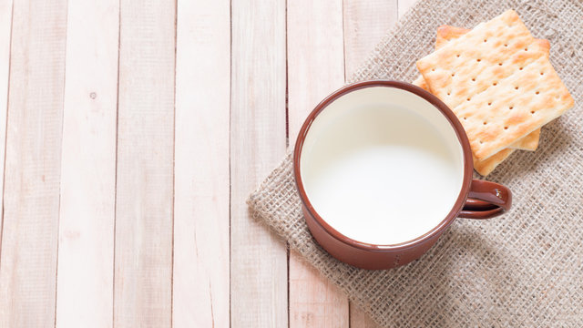 Milk with crackers on wooden table.