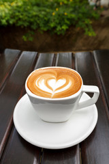 Cup of latte coffee on wood background