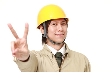young Japanese construction worker showing a victory sign