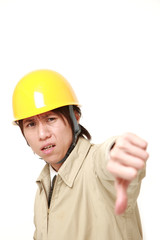young Japanese construction worker with thumbs down gesture