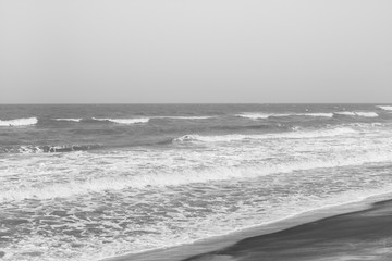 Frothy waves on beach with patterns - Incoming frothy sea waves on a tropical beach. These rushing waves leave curved patterns on the beach. Black and white image.
