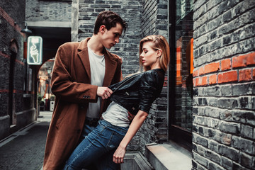 Fototapeta na wymiar Young trendy man and woman posing in brick walls street 