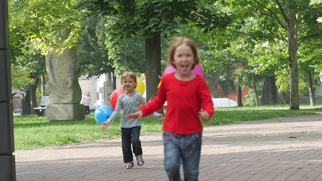 two little sisters with balloons running in the park, Slow motion