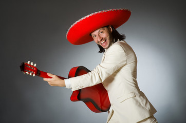 Funny mexican in suit holding guitar against gray
