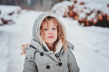 child girl on cozy snowy walk in winter forest