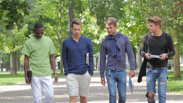 Happy men students walking together on campus. slow motion