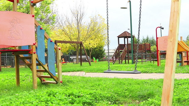 empty swing with chains swaying at playground for child, moved from wind, on green meadow background, hd 1080p