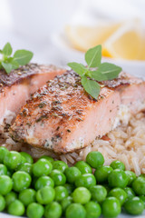 Baked salmon with rice, green peas and basil on a white ceramic plate on a white background. Closeup..