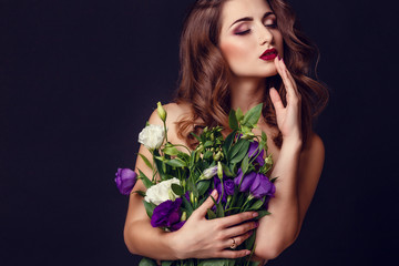 fashion studio photo of beautiful brunette woman with bright makeup with a bouquet of purple and white eustoma