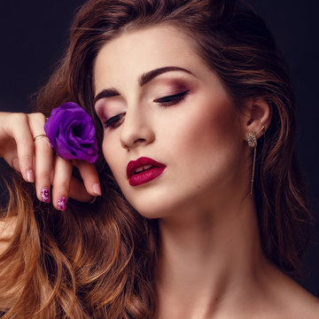 fashion studio photo of beautiful brunette woman with bright makeup with a bouquet of purple and white eustoma