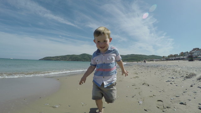 Happy active child boy running on the beach and enjoying sunny day in Spain.