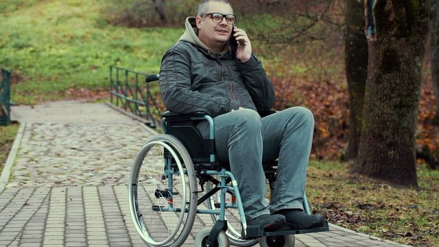 Disabled man talking on smartphone in wheelchair