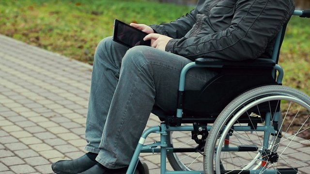 Disabled man with tablet PC in wheelchair