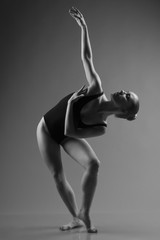 Modern ballet dancer posing on dark background