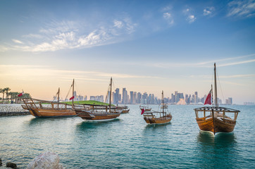 Naklejka premium Dhows moored off Museum Park in central Doha, Qatar, Arabia, with some of the buildings from the city's commercial port in the background.