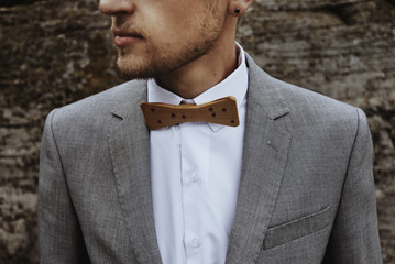 happy stylish elegant groom in the gray suit with a bow tie on t